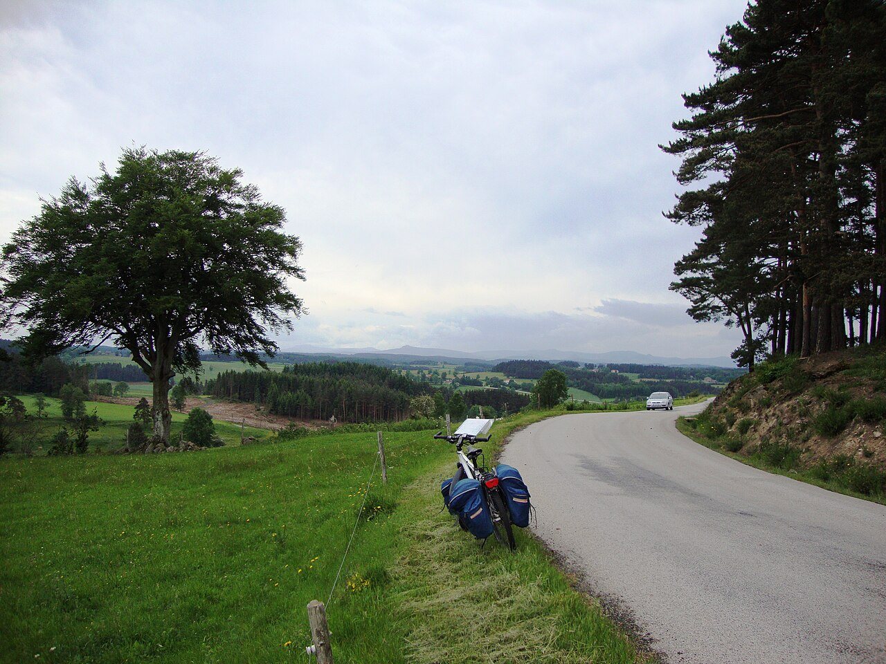 A touring bicycle beside a rural road in France; an illustration of cycle-trip planning.
