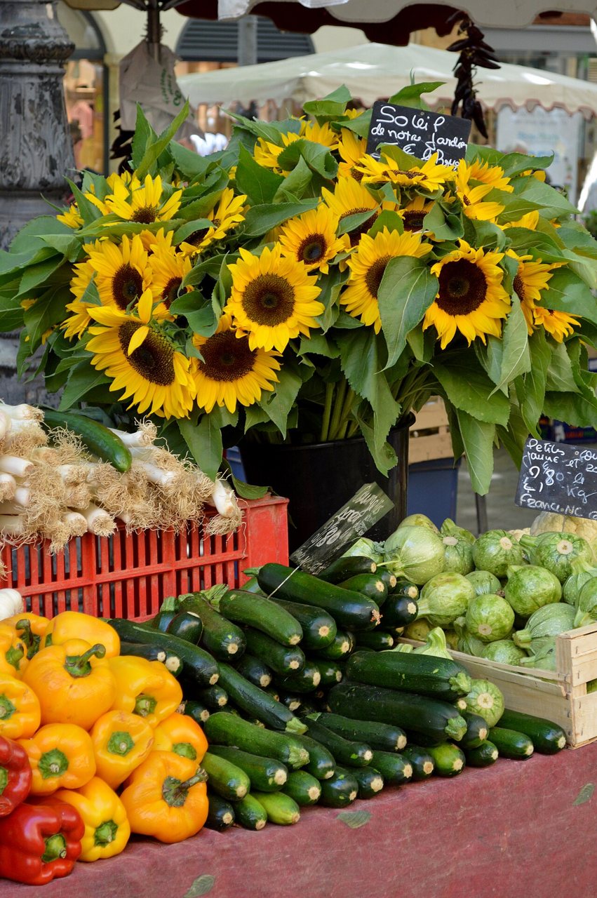 Vegetables and sunflowers at a market in France, illustrating food provenance and seasonality.